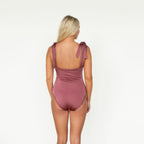 Woman wearing a mauve one-piece swimsuit on a white background