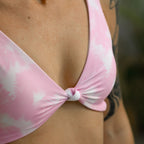 Close-up of a pink tie-dye bikini top worn by a person.