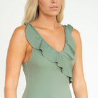 Green dress with ruffled neckline worn by a model on a white background