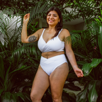 Woman in a white bikini standing among green plants