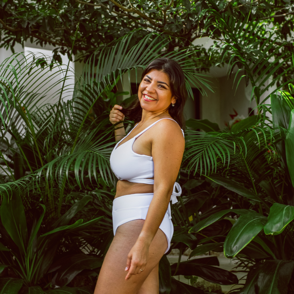 Woman in a white bikini standing among green plants