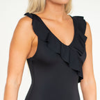 Black sleeveless swimsuit with ruffled shoulders on a model against a white background