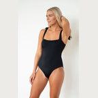 Woman wearing a black swimsuit against a white background