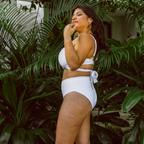 Woman in a white bikini standing among green plants