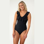 Woman wearing a black one-piece swimsuit with ruffle details on a white background