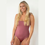Woman wearing a mauve swimsuit against a white background