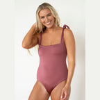 Woman wearing a mauve one-piece swimsuit on a white background