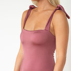 Mauve tank top with tied straps worn by a person on a white background