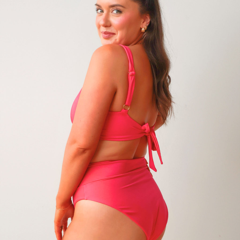 Woman wearing a pink bikini against a plain background